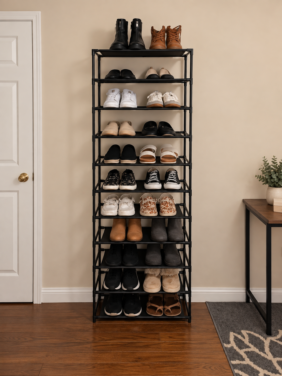 A tall narrow black rack organizing 22 pairs of shoes beside a bedroom door