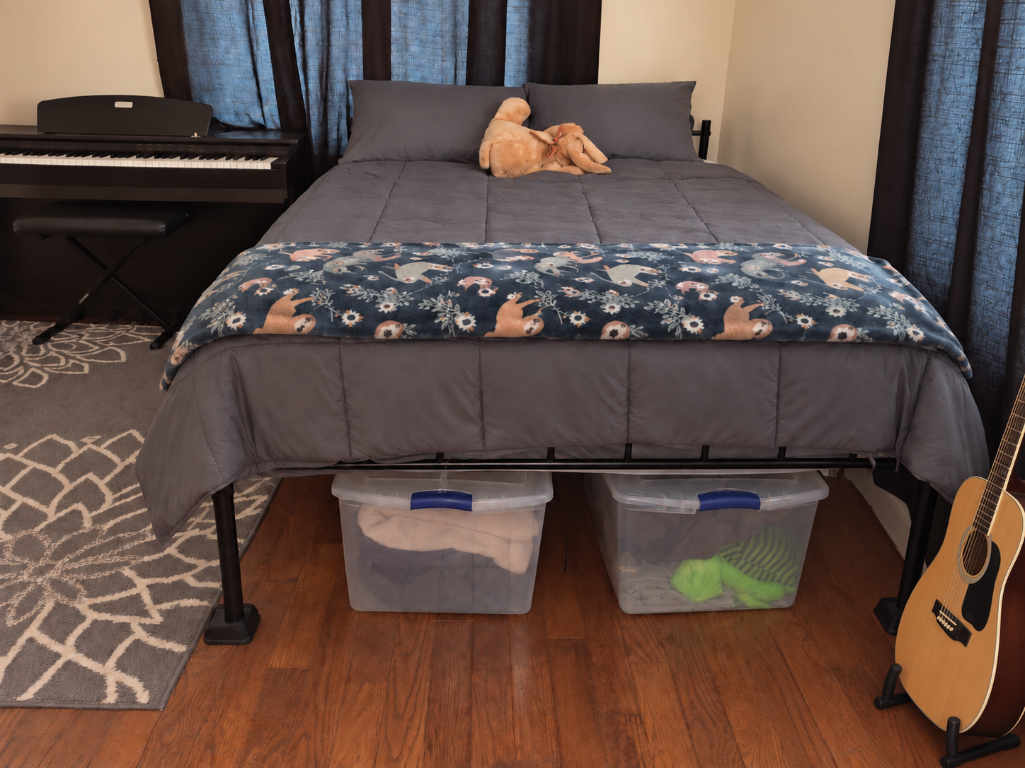 A tidy bedroom with four clear storage bins arranged beneath a neatly made bed