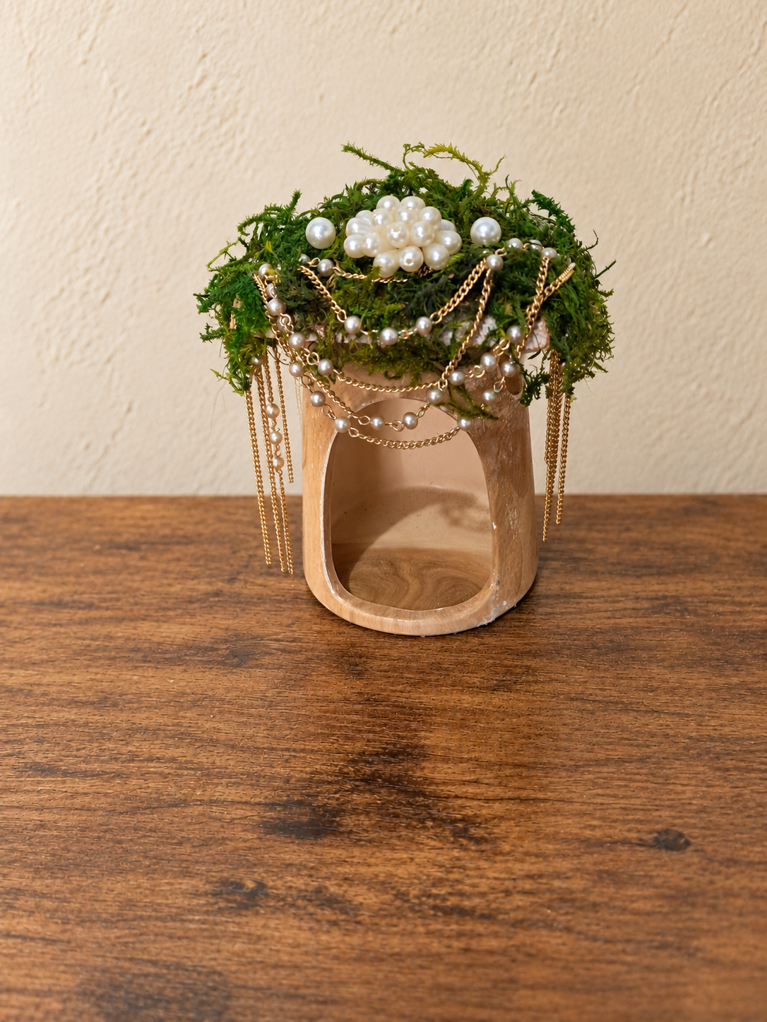 Side angle of the fairy house showing its moss roof, pearl ornament, and freely hanging gold chains
