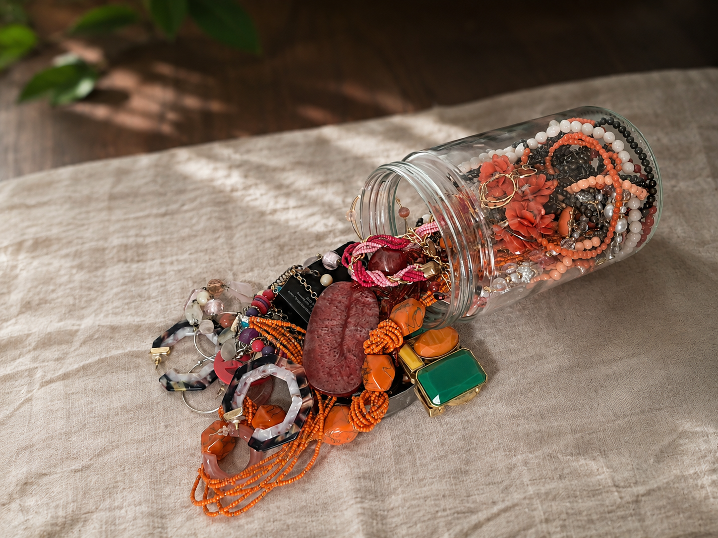 Coral and pink thrifted jewelry spilling from a glass jar