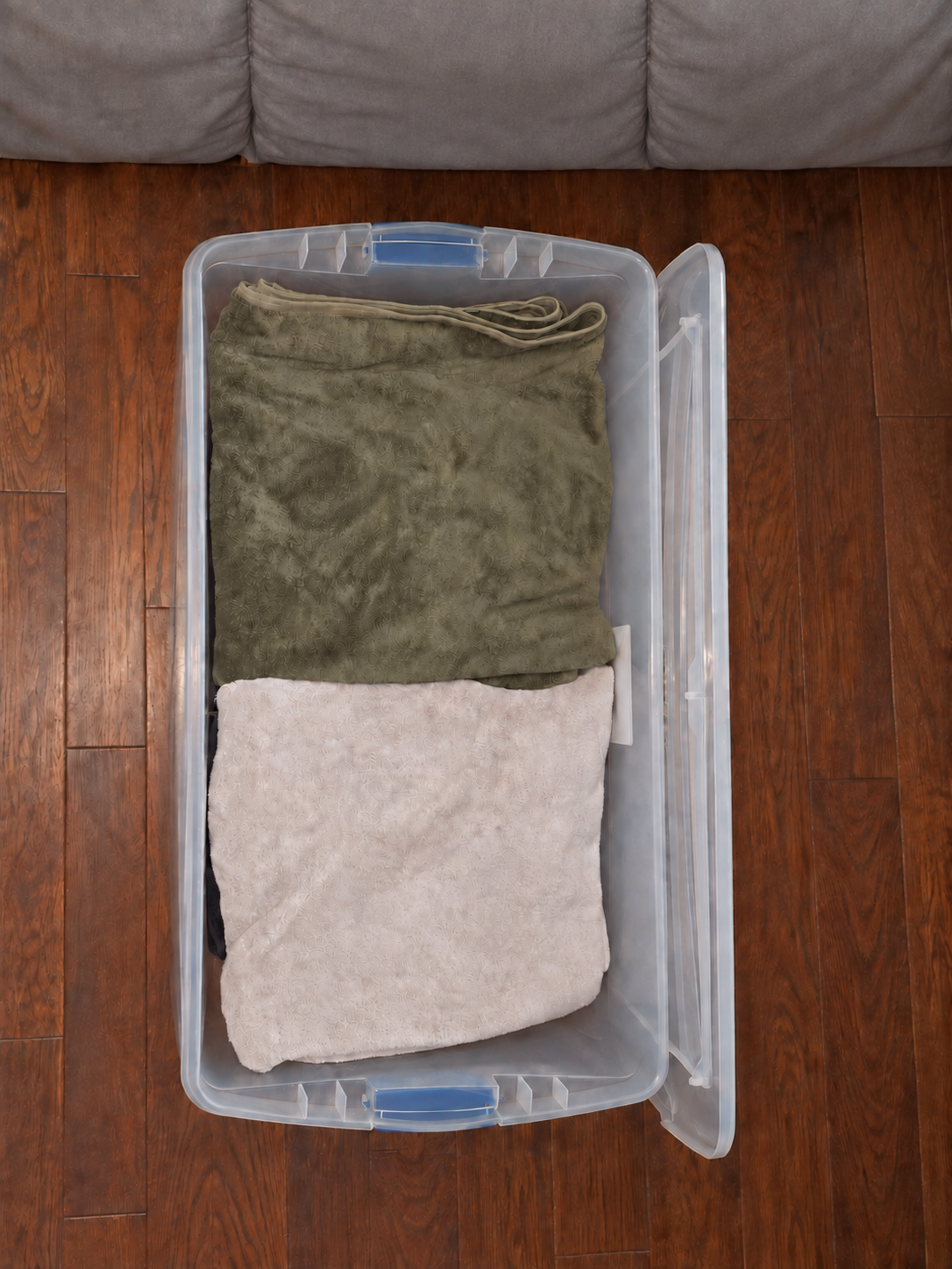 An open clear under-bed bin holding neatly folded towels
